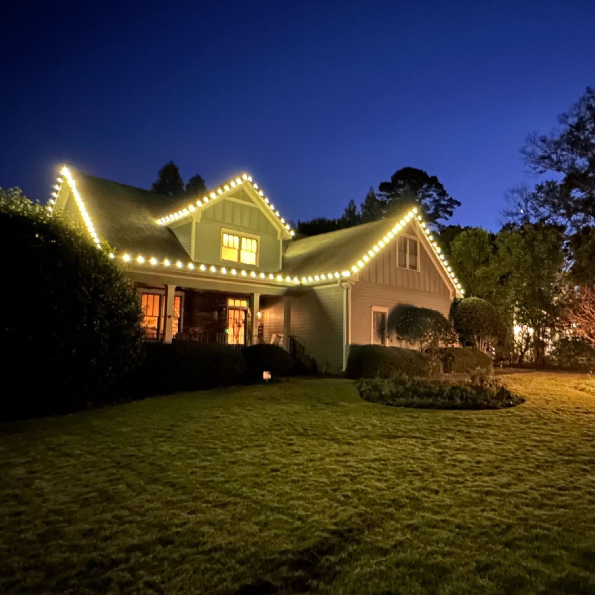 Craftsman house with warm white holiday lights at dusk